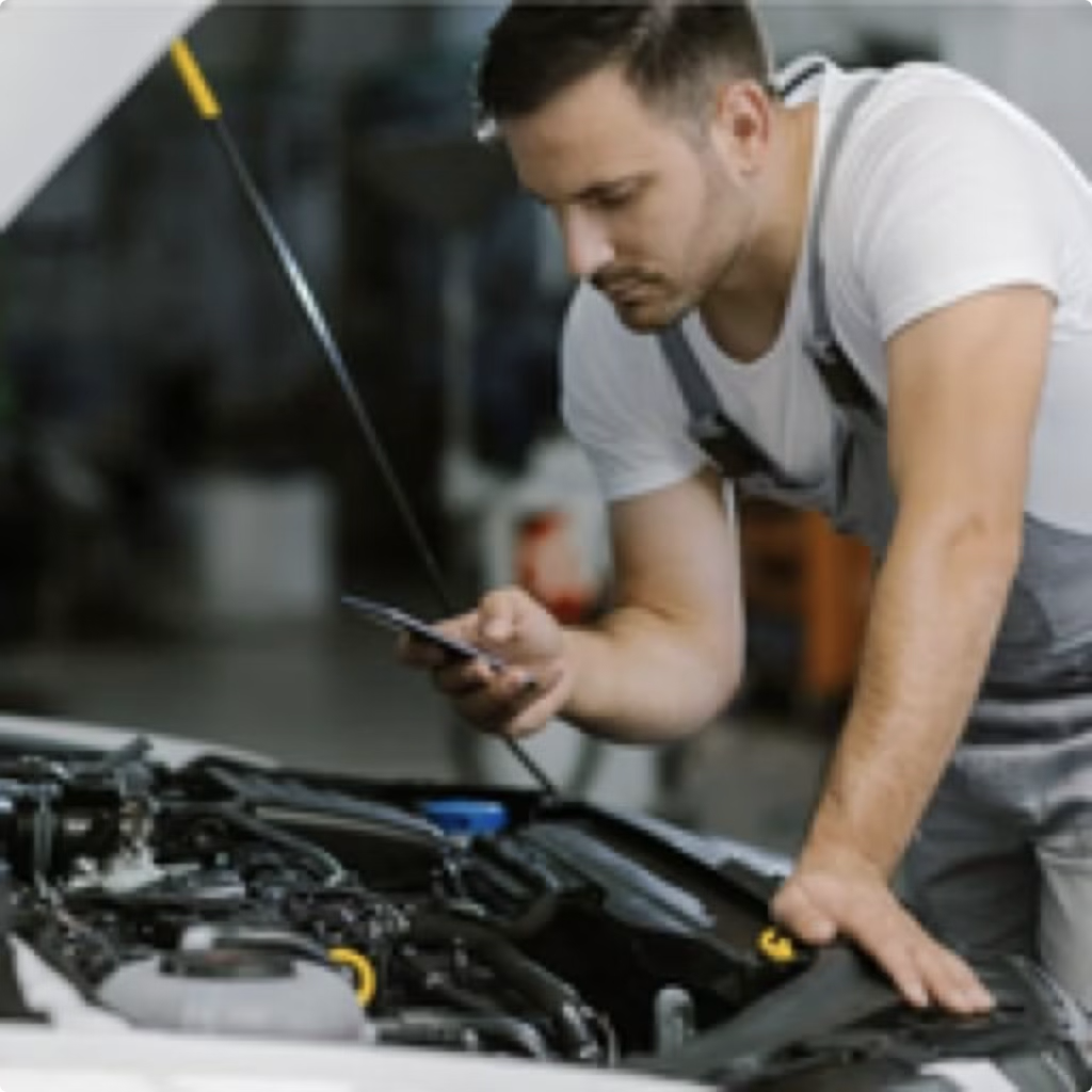 Mechanic using smartphone at vehicle engine bay